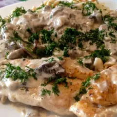 Pyszny kurczak z mascarpone i grzybami w kremowym sosie, podany z makaronem i posypany świeżym koperkiem.