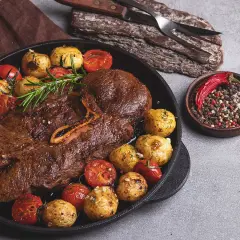 Stek z dziczyzny z pieczonymi ziemniakami, pomidorkami i mieszanką pieprzu.