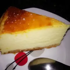 Pyszny sernik z jogurtu greckiego z lekko przypieczoną górką, podany na białym talerzu. Idealny na deser.