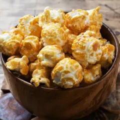 Pyszny karmelowy popcorn w drewnianej misce. Idealny przepis na to, jak zrobić popcorn w garnku, by uzyskać taki efekt.