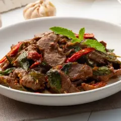 Aromatyczna wołowina po wietnamsku z bazylią i papryczką chili, podana w białej misce.