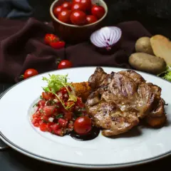 Soczysty udziec wołowy z sałatką pomidorową i ziemniakami. Idealny posiłek dla smakoszy.