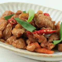 Pyszny kurczak po wietnamsku z papryczkami chili i zieloną cebulką na talerzu.