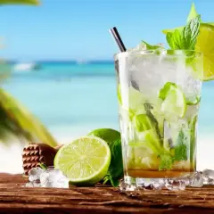 Orzeźwiający mojito bezalkoholowe z limonką i miętą na tle plaży. Idealny na upalne dni.