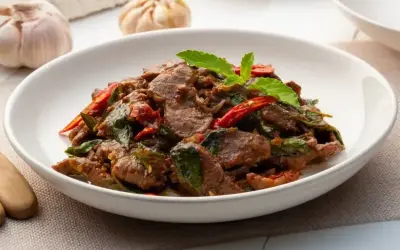 Aromatyczna wołowina po wietnamsku z bazylią i papryczką chili, podana w białej misce.