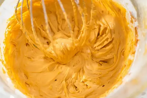 Mieszadło miksuje gładką, kremową masę kajmakową w misce.