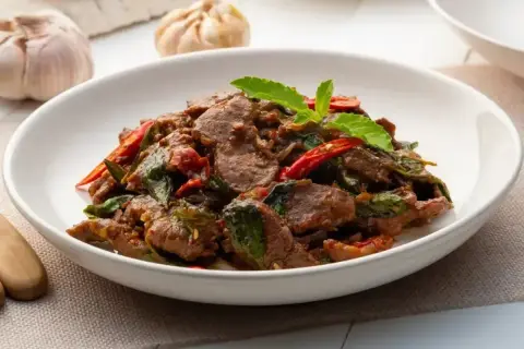 Aromatyczna wołowina po wietnamsku z bazylią i papryczką chili, podana w białej misce.