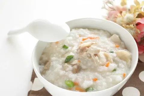 Miseczka pysznego congee z kurczakiem i warzywami, gotowa do spożycia.