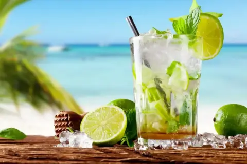 Orzeźwiający mojito bezalkoholowe z limonką i miętą na tle plaży. Idealny na upalne dni.