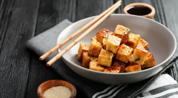 Chrupiące kostki tofu w sosie, pałeczki i sezam. To pyszne danie pokazuje, co to tofu.