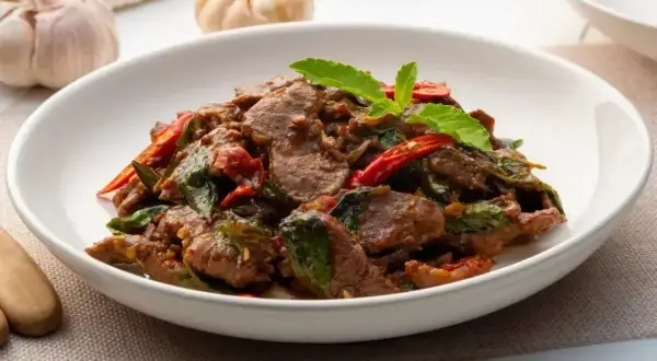 Aromatyczna wołowina po wietnamsku z bazylią i papryczką chili, podana w białej misce.