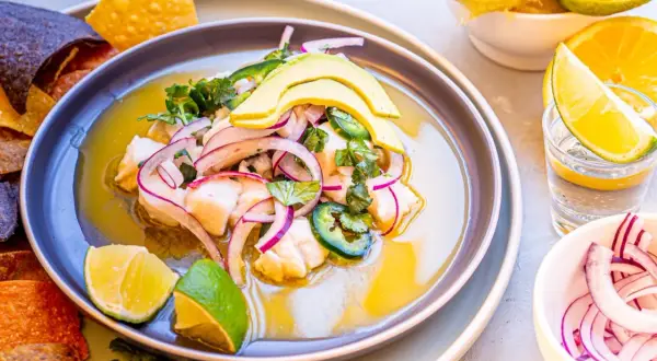 Pyszne ceviche z rybą, awokado, czerwoną cebulą i jalapeno, podane z nachos i limonką.