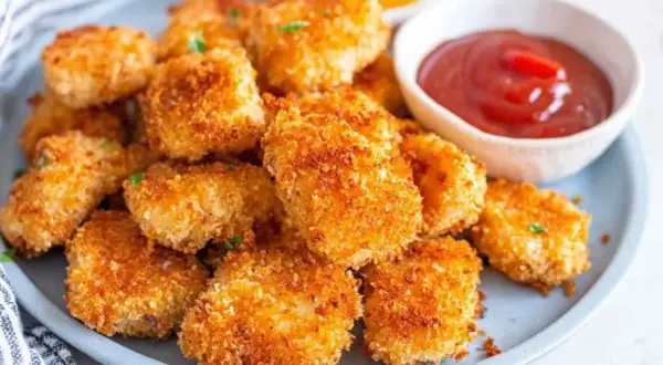 Chrupiące nuggetsy z airfryer na talerzu, obok miseczka ketchupu. Idealna przekąska!