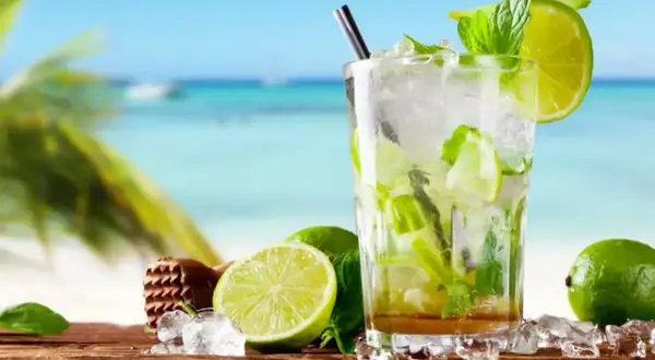 Orzeźwiający mojito bezalkoholowe z limonką i miętą na tle plaży. Idealny na upalne dni.