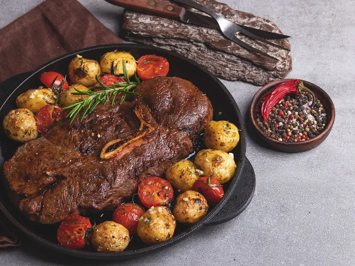 Stek z dziczyzny z pieczonymi ziemniakami, pomidorkami i mieszanką pieprzu.