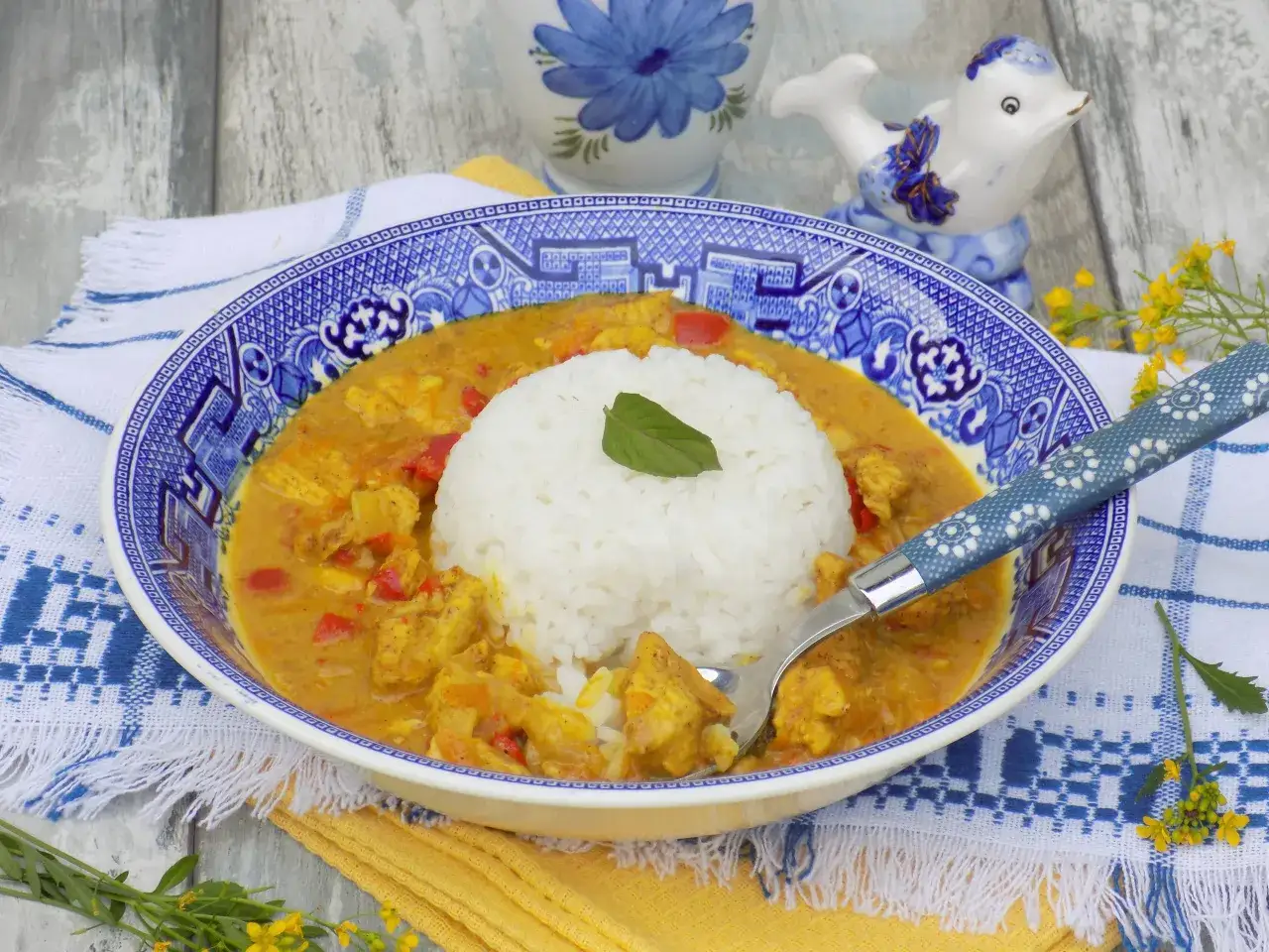 Aksamitny kurczak curry z ryżem, podany w ozdobnej misce, z widelcem gotowym do degustacji.