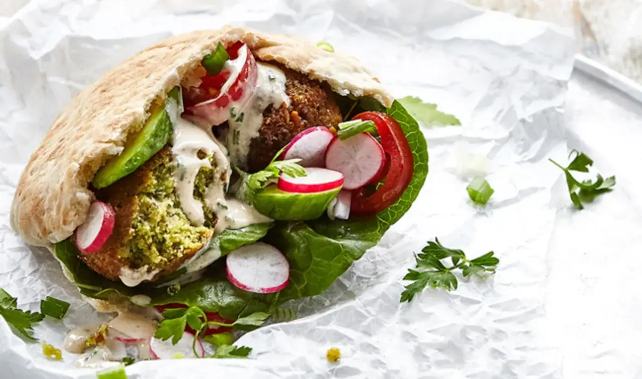 Pyszny falafel w picie z warzywami i sosem. Zastanawiasz się, falafel co to? To aromatyczne kotleciki z ciecierzycy!