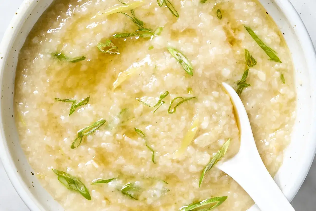 Gęsty, kremowy congee z ryżu, ozdobiony szczypiorkiem i imbirem, gotowy do podania.