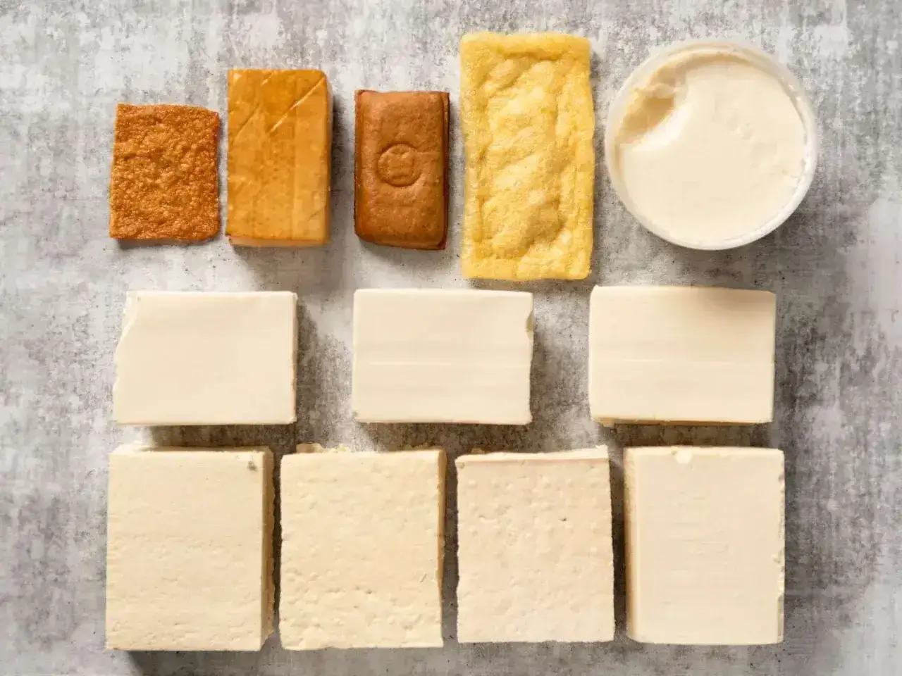 Różne rodzaje tofu: kostki, w plastrach, smażone i kremowe. To pokazuje, co to tofu i jego wszechstronność.