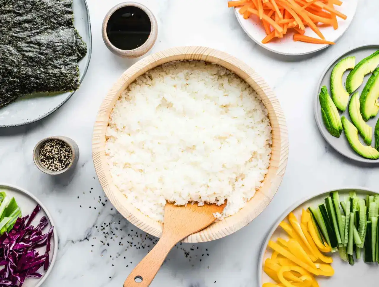 Gotowy ryż do sushi na 500g, obok nori, awokado, marchewka, ogórek, papryka i sos sojowy.