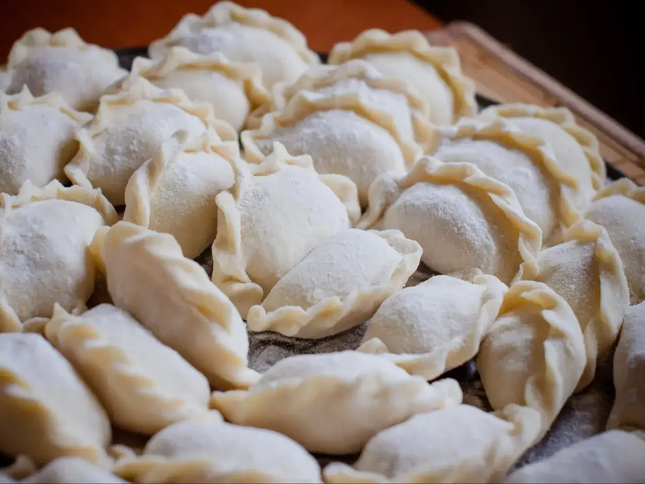Mnóstwo surowych pierożków dim sum, oprószonych mąką, czeka na ugotowanie.