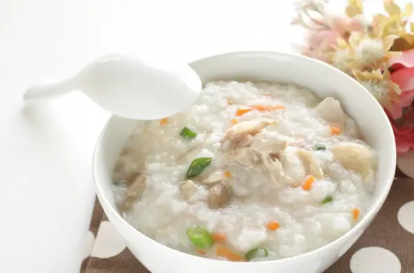 Miseczka pysznego congee z kurczakiem i warzywami, gotowa do spożycia.