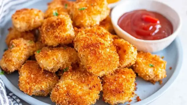 Chrupiące nuggetsy z airfryer na talerzu, obok miseczka ketchupu. Idealna przekąska!
