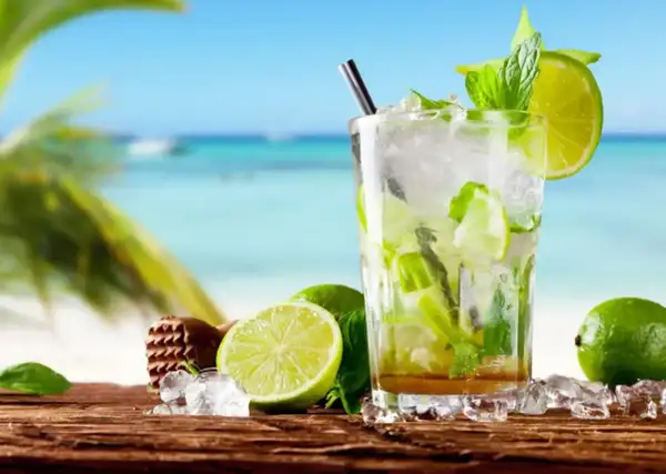 Orzeźwiający mojito bezalkoholowe z limonką i miętą na tle plaży. Idealny na upalne dni.